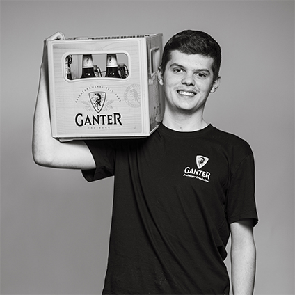 schwarz-weiß Portrait eines Mannes, der eine Bierkiste auf der Schulter trägt