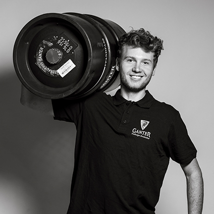schwarz-weiß Portrait eines Mannes, der ein Bierfass auf der rechten Schulter trägt